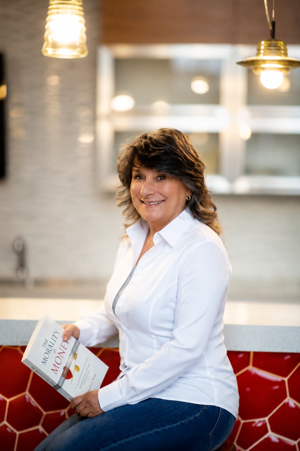 Renée E. Bryan smiling and holding her book The Morality of Money